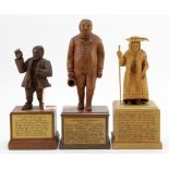 Three hand carved wooden figures, depicting interesting characters in history, each mounted on a