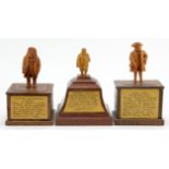 Three hand carved wooden figures, depicting interesting characters in history, each mounted on a