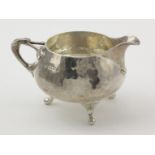 Silver Arts & Crafts milk jug, raised on three feet, hallmarked 'C.E (Charles Edwards) London 1930',