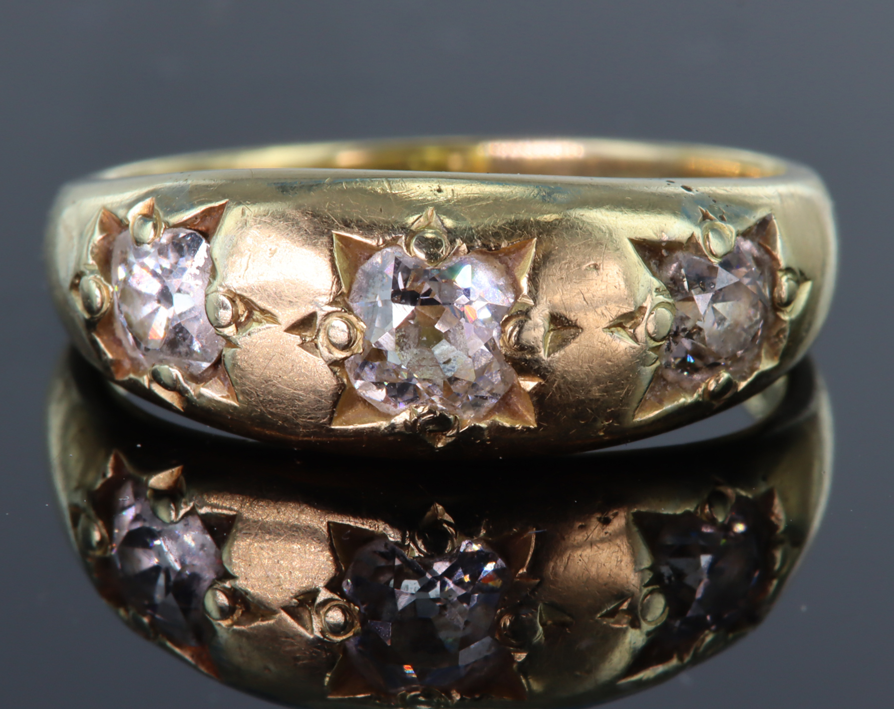 Tests as 15ct yellow gold gypsy set three stone ring set with three old cut diamonds, centre diamond