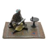 Cold painted bronze, depicting a figure sat reading on a carpet, with Franz Bergman stamp to base,