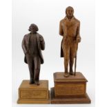 Two hand carved wooden figures, depicting interesting characters in history, each mounted on a