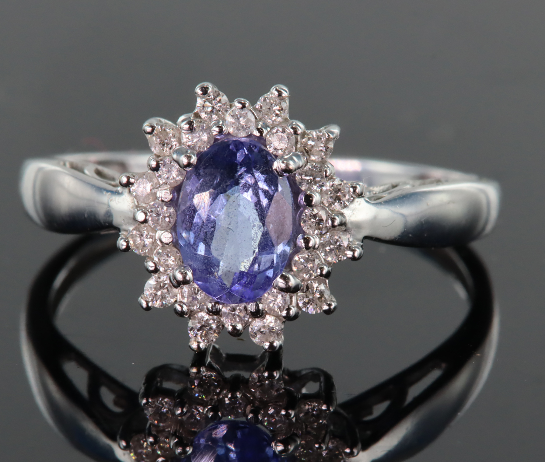 18ct white gold ring set with central oval tanzanite measuring approx. 7mm x 5mm, surrounded by a