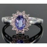 18ct white gold ring set with central oval tanzanite measuring approx. 7mm x 5mm, surrounded by a