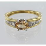 18ct yellow gold ring set with a central oval imperial topaz with diamond set shoulders, finger size