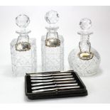 Three cut glass decanters with stoppers, two with silver hallmarked spirit labels (Whisky & Gin),