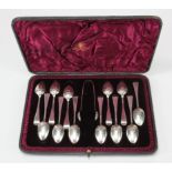 Boxed set of twelve silver spoons wih a set of sugar tongs. All depicting a ship and hallmarked