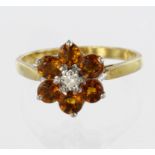 18ct yellow gold cluster ring set with a central diamond surrounded by six round orange sapphires,