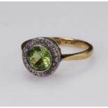 18ct and platinum ring set with a round peridot measuring approx. 6.5mm in a rub over setting,
