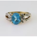 9ct yellow gold ring set with an oval blue topaz measuring approx. 9mm x 7mm, with ten diamonds