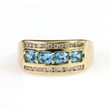 9ct yellow gold flared head band ring set with four oval blue topaz in a low claw setting,