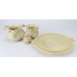 Four items of Belleek bearing black marks. To include twin handled woven bread plate (repaired), pin