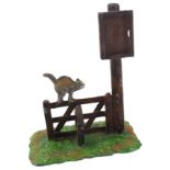 Heyde. Knick-knack/nippes cat on a fence with shackles rasied looking at an empty sign, 14cm high.