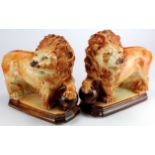 Pair of Staffordshire lions with one paw resting on a ball on a raised plinth. Approximately 33cm