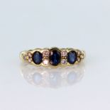 18ct yellow gold ring set with three graduated oval sapphires divided by four round brilliant cut