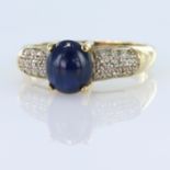 9ct yellow gold ring set with an oval sapphire cabochon measuring approx. 8mm x 7mm, with thirteen