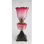 Oil Lamp. An iron based oil lamp, circa late Victorian, with inner glass tube & cranberry glass