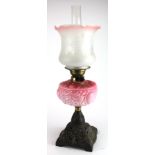 Oil Lamp. An iron based oil lamp, circa late Victorian, with inner glass tube & frosted / pink glass