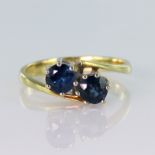 14ct yellow gold crossover style ring set with two round sapphires measuring approx. 4.5mm diameter,