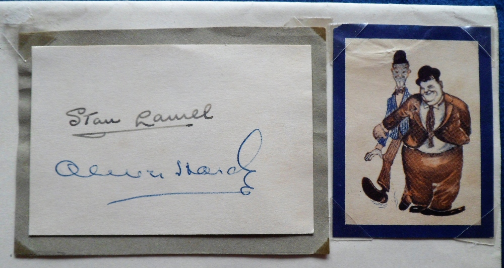 Autographs, a signed piece of card by Stan Laurel & Oliver Hardy,(2" x 3"), mounted on album page