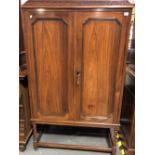 An early 20th Century rosewood Anglo-Indian cupboard, the canted top with a foliate scroll carved