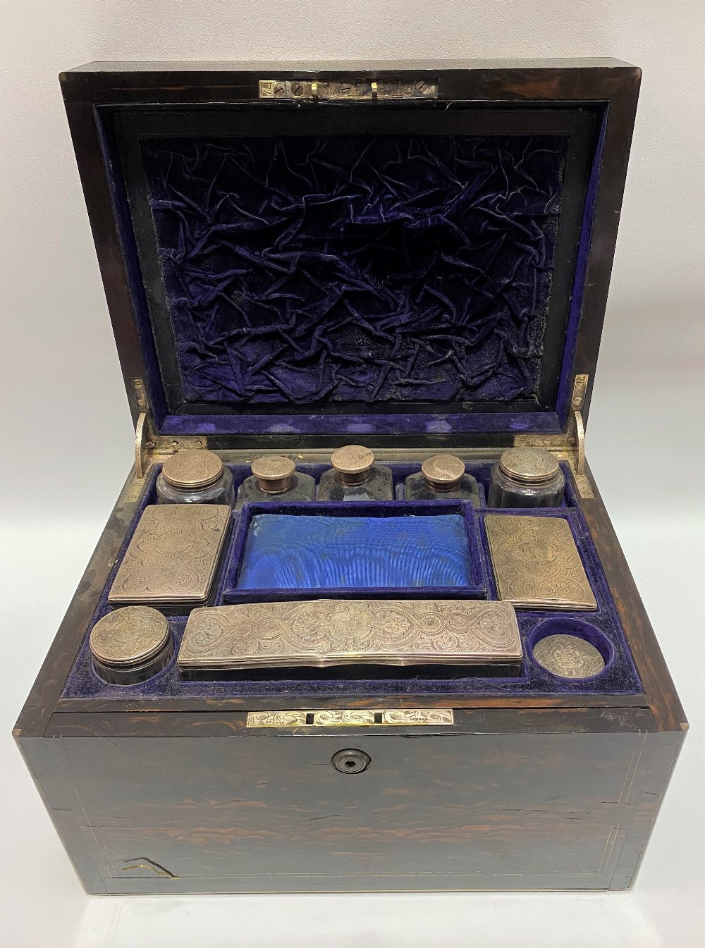 Victorian Coromandel brass inlaid vanity box, the hinged-lid revealing eight silver lidded bottles