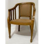 An oak elbow chair with a leather upholstered back and seat and on square tapering legs with spade
