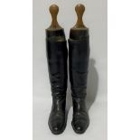 A pair of black leather riding boots with wooden tree lasts, length of sole 26cm.