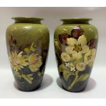 A pair of Burmantofts faience floral decorated vases upon a green and brown blush ground, both