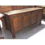 17th/18th Century oak four panelled coffer, the hinged moulded two plank top over a lunette carved