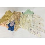 A bag of textiles, including various pairs of silk stockings, lace and silk baby's dresses etc.