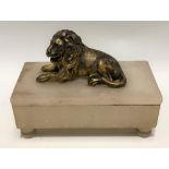 Gilt metal recumbent lion on an alabaster rectangular stand. width 17cm.