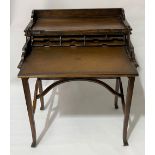 A 20th Century teak writing table, the rectangular hinged moulded top ratcheted to reveal a brown