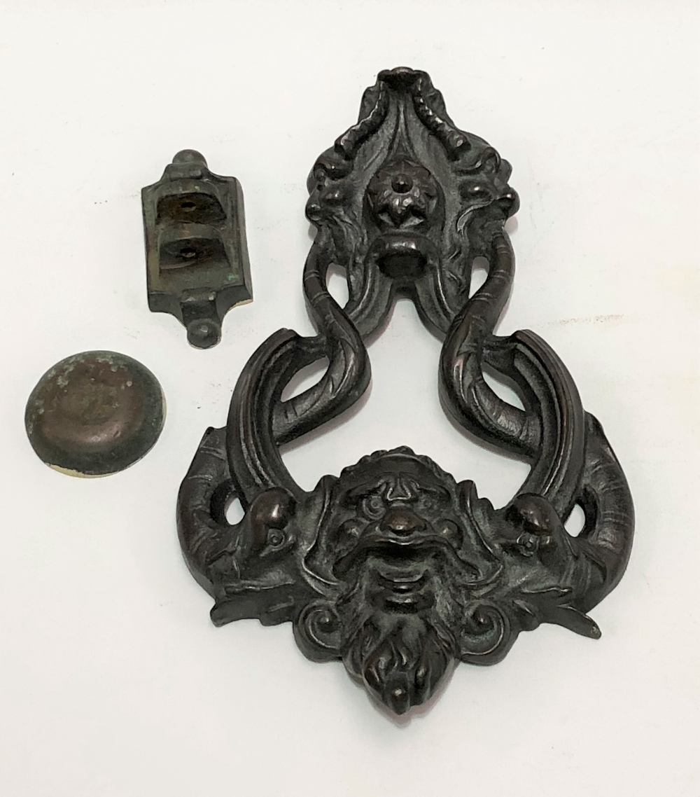A large 19th Century door knocker cast with a grotesque bearded mask flanked by two coiled dolphins,