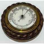 An aneroid barometer within a carved oak rope twist case, diameter 19cm.