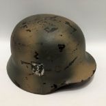 A WWII German Third Reich helmet, the side with SS decal and camouflage painted.