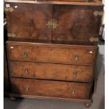 A walnut veneered linen cupboard, the moulded top over a pair of cupboard doors with brass strap