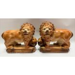 A pair of Staffordshire Pottery opposing lions, their front paws resting on a ball, both with
