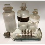 Three chemist bottles together with a ship in a bottle (4)