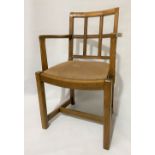 An oak elbow chair with leather upholstered drop-in seat after a design by Heals