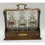 An oak brass bound three-section tantalus enclosing three square section spirit bottles with