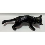 Humorous black glazed pottery wall hanging model of a cat with glass inset eyes, length 46cm