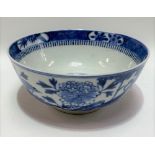 A Chinese blue and white underglaze bowl decorated with a pine tree and rocks issuing flowers and