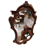 A French style mahogany carved shaped wall mirror, the shield shaped plate with bevel edging, within