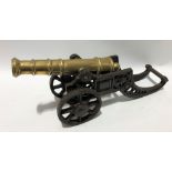 A brass model cannon upon cast iron truck, barrel length 9.5in, length overall 46cm