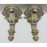 A pair of white painted and gilded corner wall hanging brackets with leaf scroll carved supports,