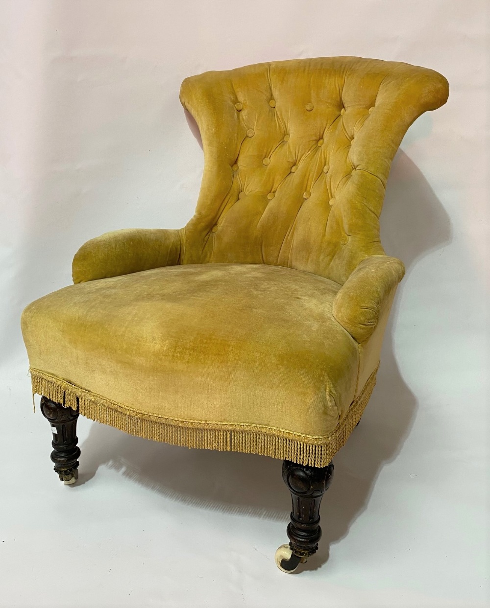 Victorian button-back nursing chair with turned and fluted fore legs with ceramic castors