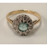 An 18ct gold emerald and diamond cluster ring, the central emerald of 0.25ct spread approx, size