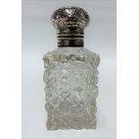An Edwardian silver lidded cut glass scent bottle, the silver embossed hinge lid with basket and