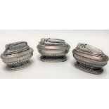 Set of three silver plated oval section half fluted table lighters by Ronson, width of each 8.5cm